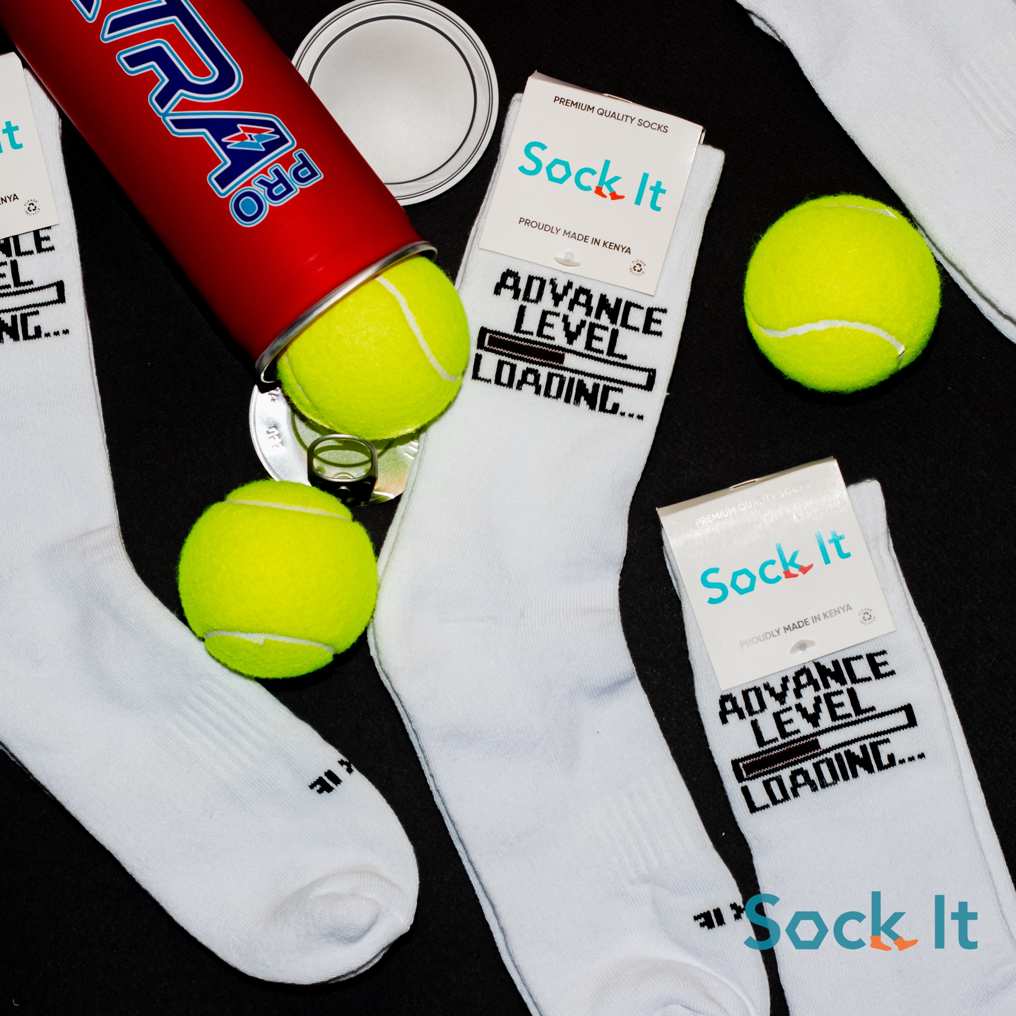 White socks with 'Sock It' branding, tennis balls, and a red canister on a black surface.