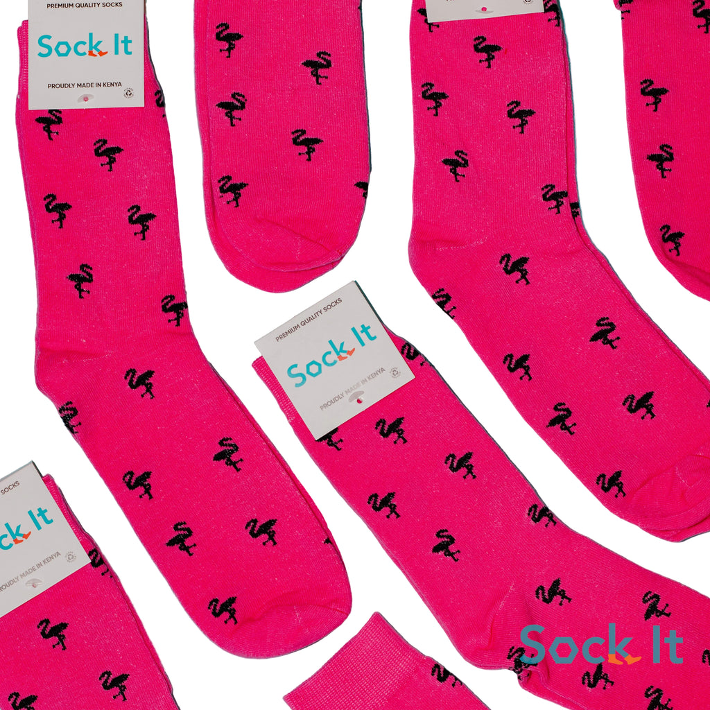 Pink socks with black flamingo pattern and 'Sock It' branding on a blue background