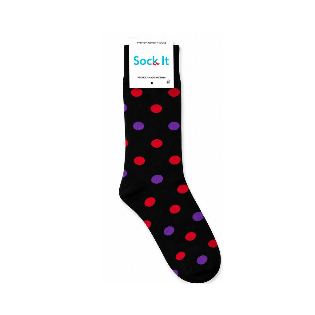 A single black crew sock with red and purple polka dots, shown on a white background with its retail paper tag attached at the top. The tag reads 'Sock It'.